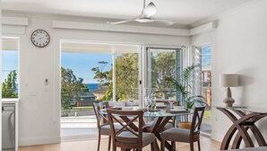 Comedor con mesa de vidrio, sillas de madera y vista al exterior.