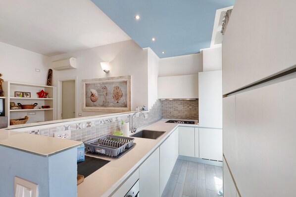 A modern kitchen with white cabinetry, a built-in stove, and a backsplash.
