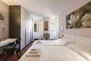 Ein Hotelzimmer mit zwei Betten, einem Schreibtisch, einem Stuhl und einem Bild an der Wand.