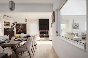 A modern dining area with a long table, chairs, and a fireplace. - Thea House Athenian Riviera (Voula)