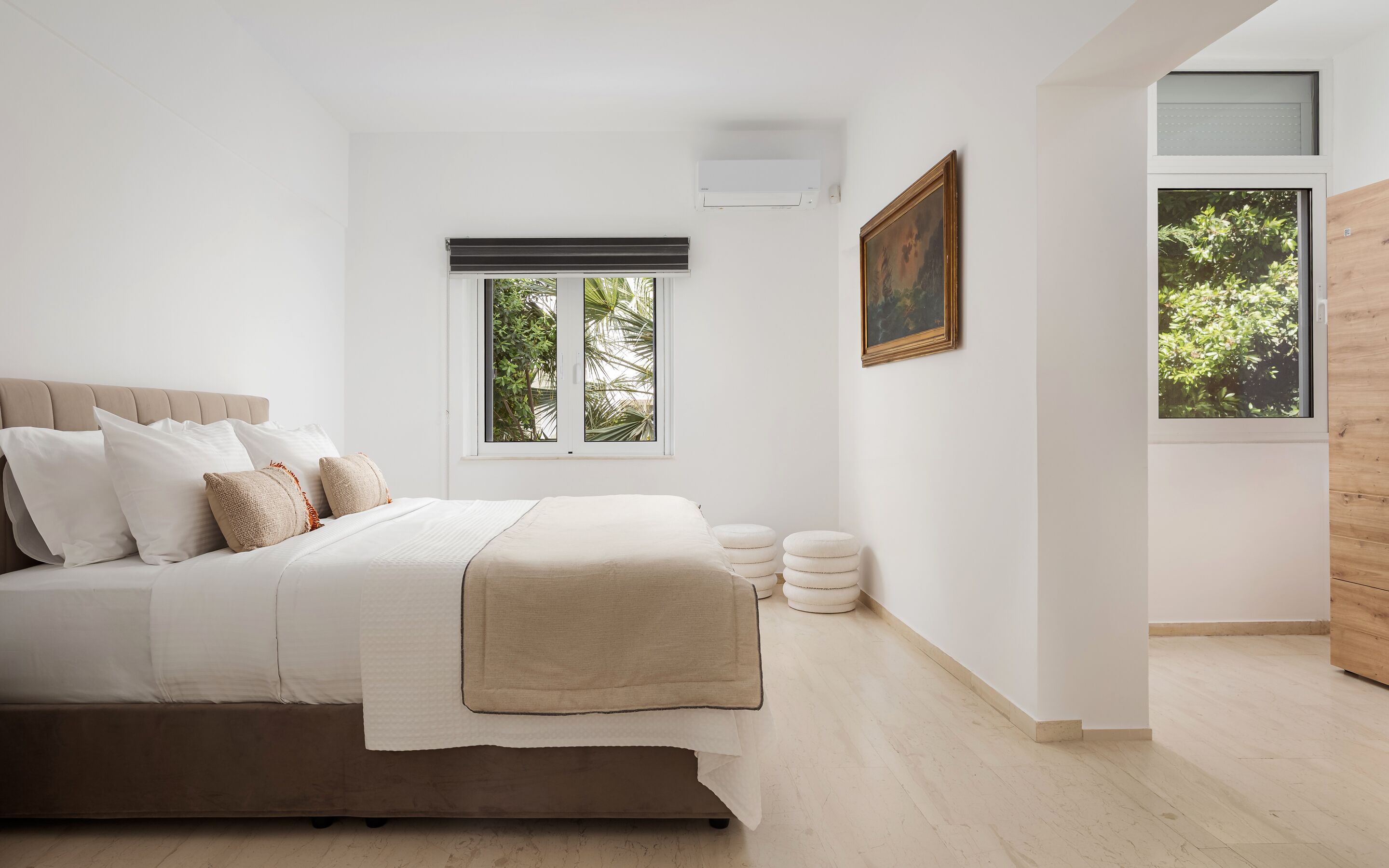 Une chambre à coucher moderne avec un lit, une fenêtre donnant sur un beau paysage, un appareil de climatisation et un tableau accroché au mur.