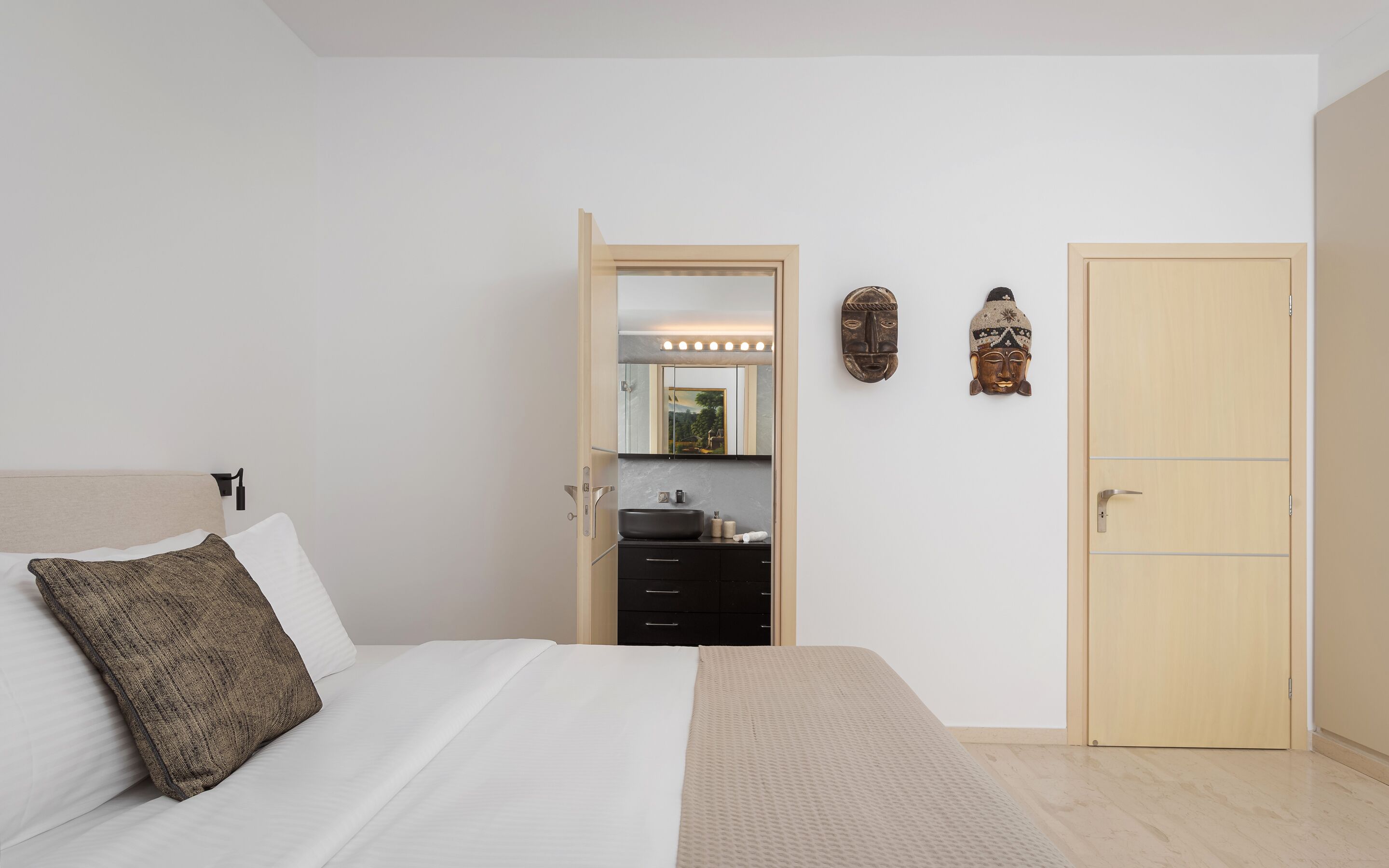 A bedroom with a bed, a dresser, a mirror, and a wardrobe.