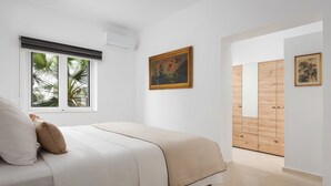 Quarto com cama, janela com persianas, quadro na parede e armário de madeira.