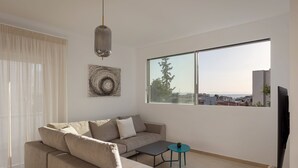Uma sala de estar moderna com um sofá, uma mesa pequena, uma TV e uma janela grande com vista para a cidade.