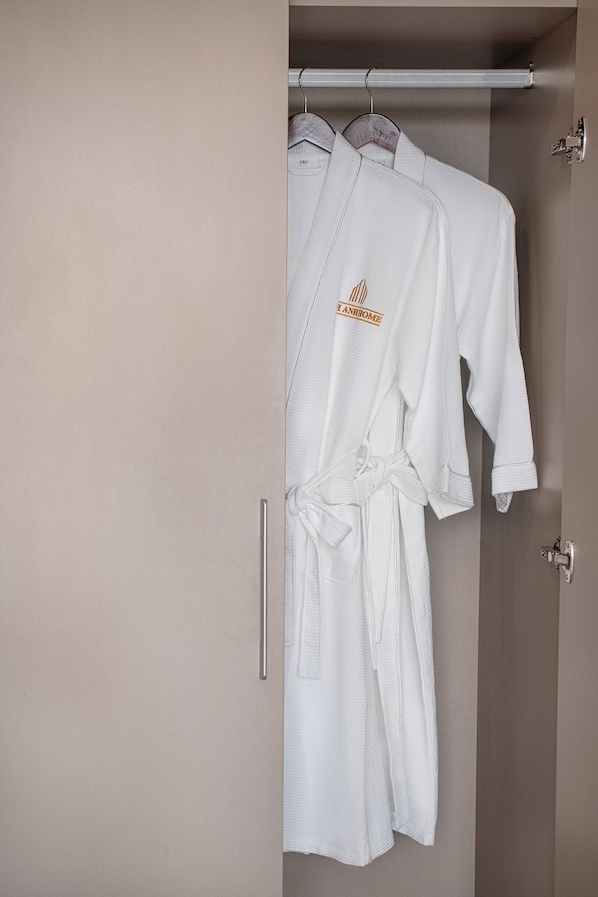 Um robe branco pendurado em um suporte fixado na parede em um quarto com cores neutras.