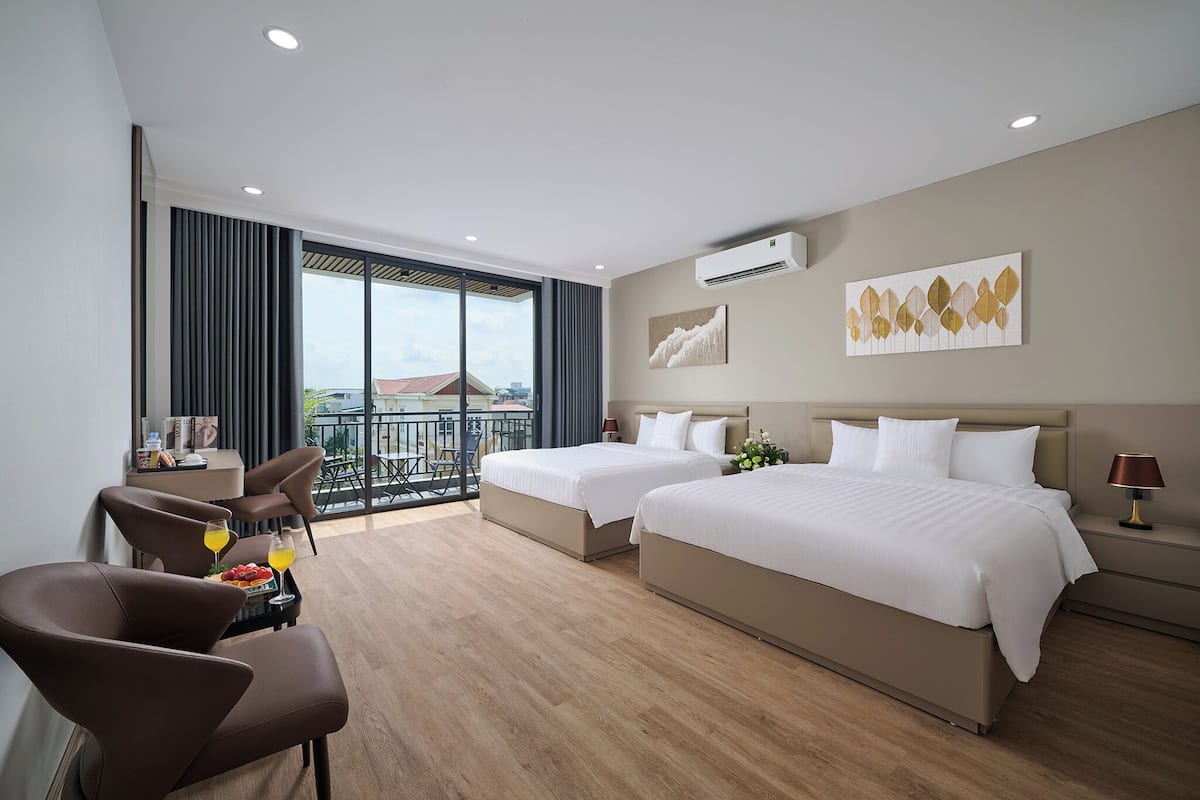 Quarto de hotel com duas camas, varanda com vista, área de refeições e design moderno.