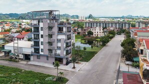 A multi-story building with balconies, a flat roof, and a view of a river and surrounding buildings. - Anh Anh Hotel Ninh Binh (Hoa Lu)