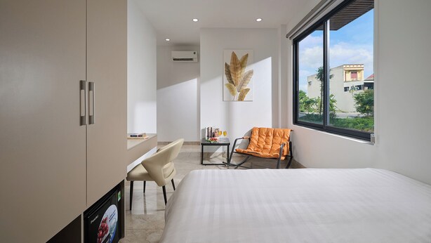 A modern hotel room with a bed, a desk, a chair, and a window with a view. - Anh Anh Hotel Ninh Binh (Hoa Lu)