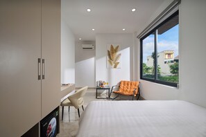Quarto de hotel moderno com cama, escrivaninha, cadeira e janela com vista.