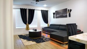 A modern living room with a black sofa, a round coffee table, and a ceiling fan. - Wonderful 4-bedroom townhome with AC in vibrant Dallas (Dallas)