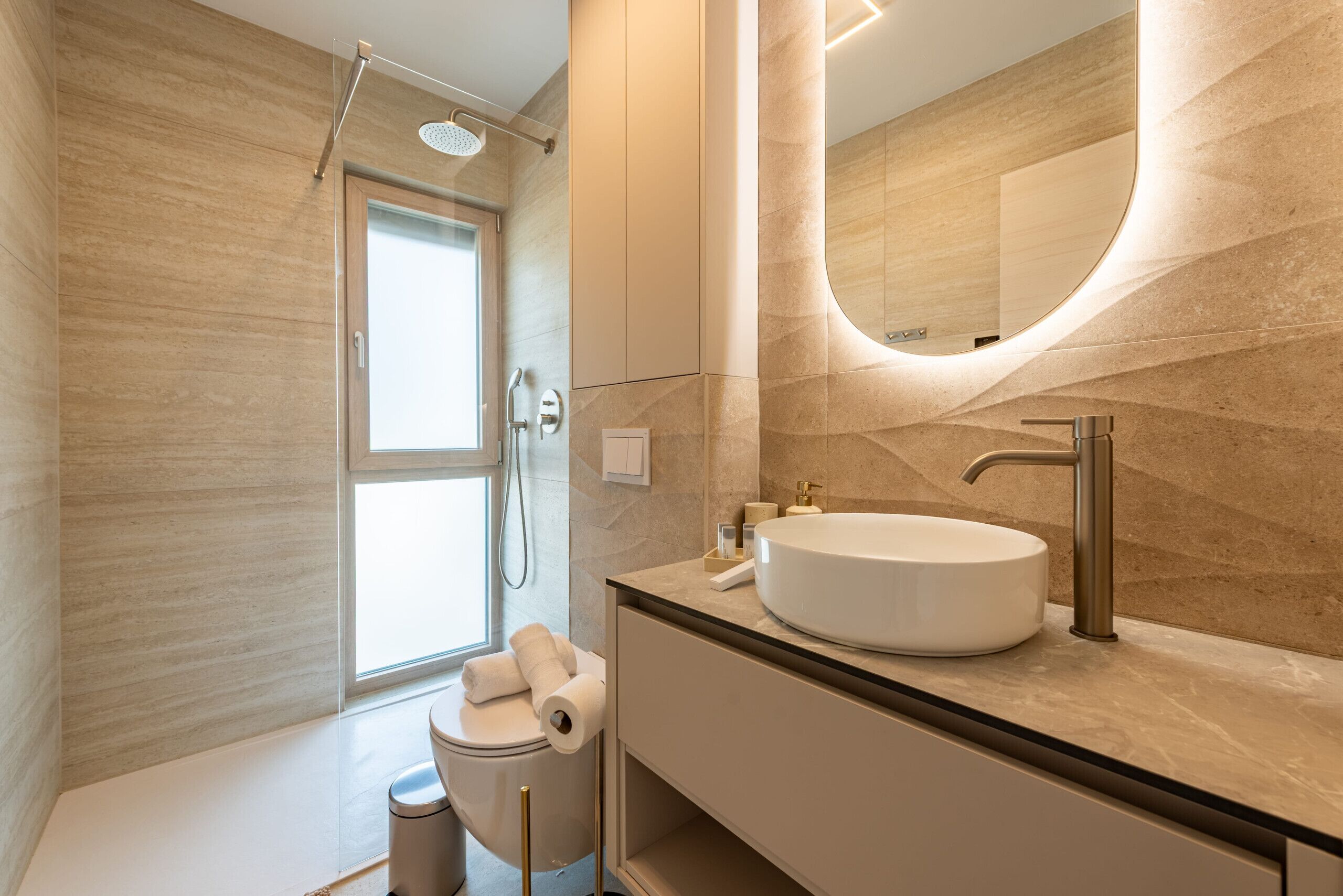 A modern bathroom with a large mirror, a round sink, and a shower.