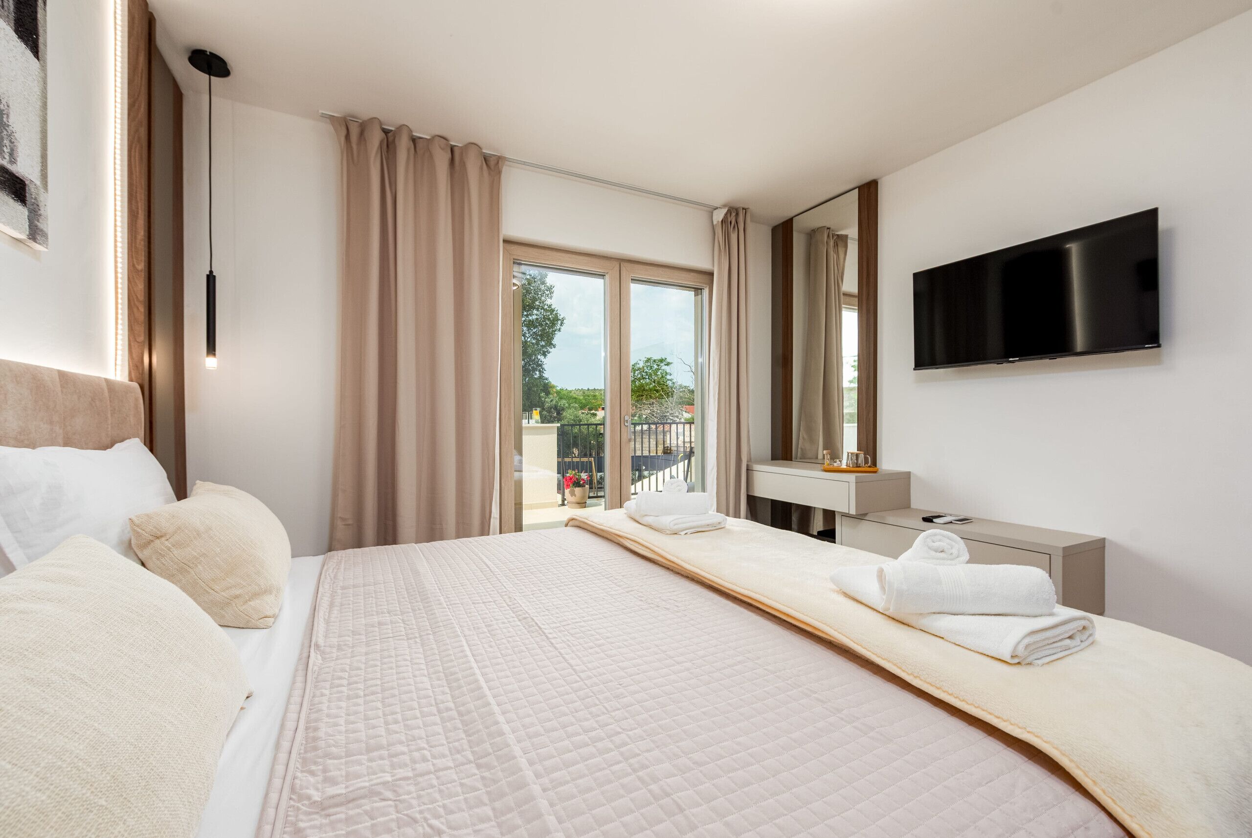 Ein Hotelzimmer mit Bett, Fernseher, Bad und Blick ins Freie.