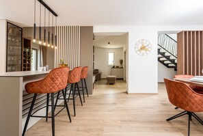 Eine moderne Küche mit einer zentralen Kochinsel, Barhocker und einem Essbereich mit Tisch und Stühlen.