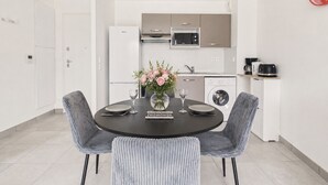 Una cocina moderna con electrodomésticos blancos, una mesa de comedor con sillas y un jarrón con flores.