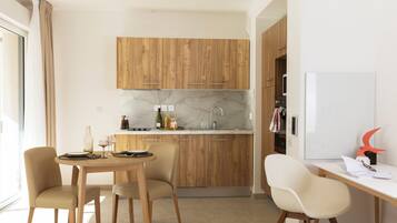 A modern kitchen with wooden cabinets, a marble countertop, and a dining area with a table and chairs.