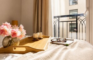 A neatly arranged bed with a tray holding a vase of flowers, two candles, and a pair of glasses. - Zenao Appart'hôtels Aix Rambot (Aix-en-Provence)