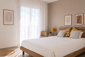 Une chambre à coucher comprenant un lit, une chaise, une table de chevet avec une lampe et des œuvres d’art accrochées aux murs.