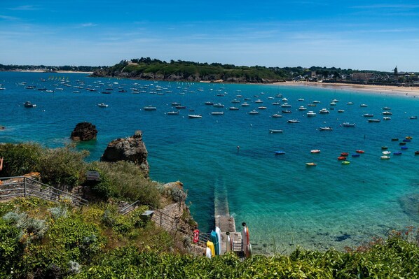A coastal view with numerous boats on the water, a rocky shoreline, and a distant building on a hill. - Superb house for 10, near beach (Dinard)