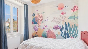 A bedroom with a bed, a window with curtains, and a wall mural of underwater scenery. - Superb house for 10, near beach (Dinard)