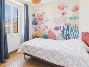 A bedroom with a bed, a window with curtains, and a wall mural of underwater scenery. - Superb house for 10, near beach (Dinard)