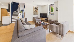A modern living room with a sofa, armchairs, a coffee table, and a TV. - Superb house for 10, near beach (Dinard)