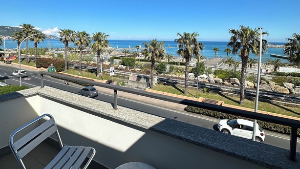 Ein Balkon mit Meerblick, ein Stuhl, ein runder Tisch und ein Geländer.