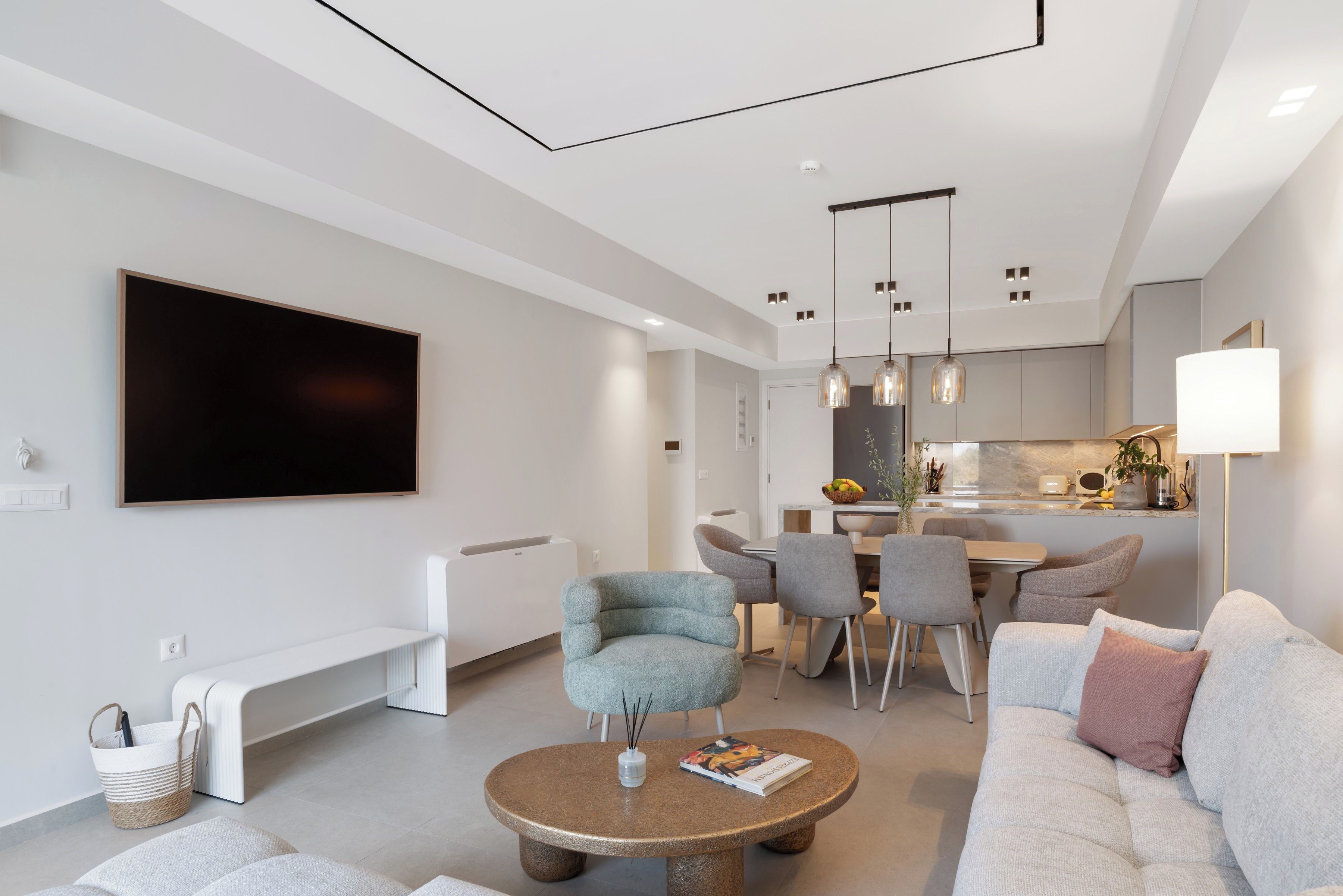 Een moderne woonkamer met een flatscreen televisie, zitplaatsen, een eethoek en een keuken.