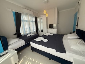 Habitación de hotel con dos camas, televisor, armario y escritorio.