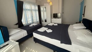 A hotel room with two beds, a TV, a wardrobe, and a bathroom. - Olivento Pansiyon (Ayvalik)