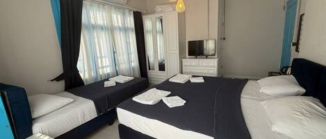 Habitación de hotel con dos camas, televisión, armario y baño.