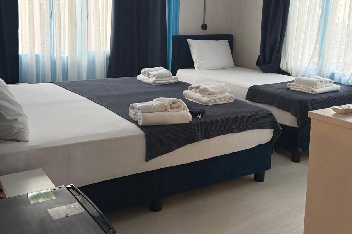 A hotel room with two beds, a desk, and a wardrobe.