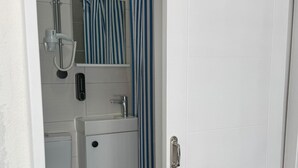 A bathroom with a toilet, a sink, a shower, and a striped curtain. - Olivento Pansiyon (Ayvalik)