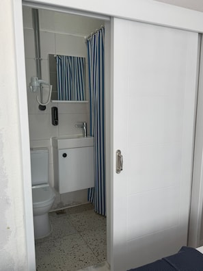 Un baño con inodoro, lavabo, ducha y una cortina a rayas.