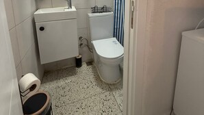 A small bathroom with a toilet, sink, and shower. - Olivento Pansiyon (Ayvalik)