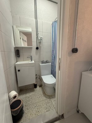 Un baño pequeño con inodoro, lavamanos y ducha.