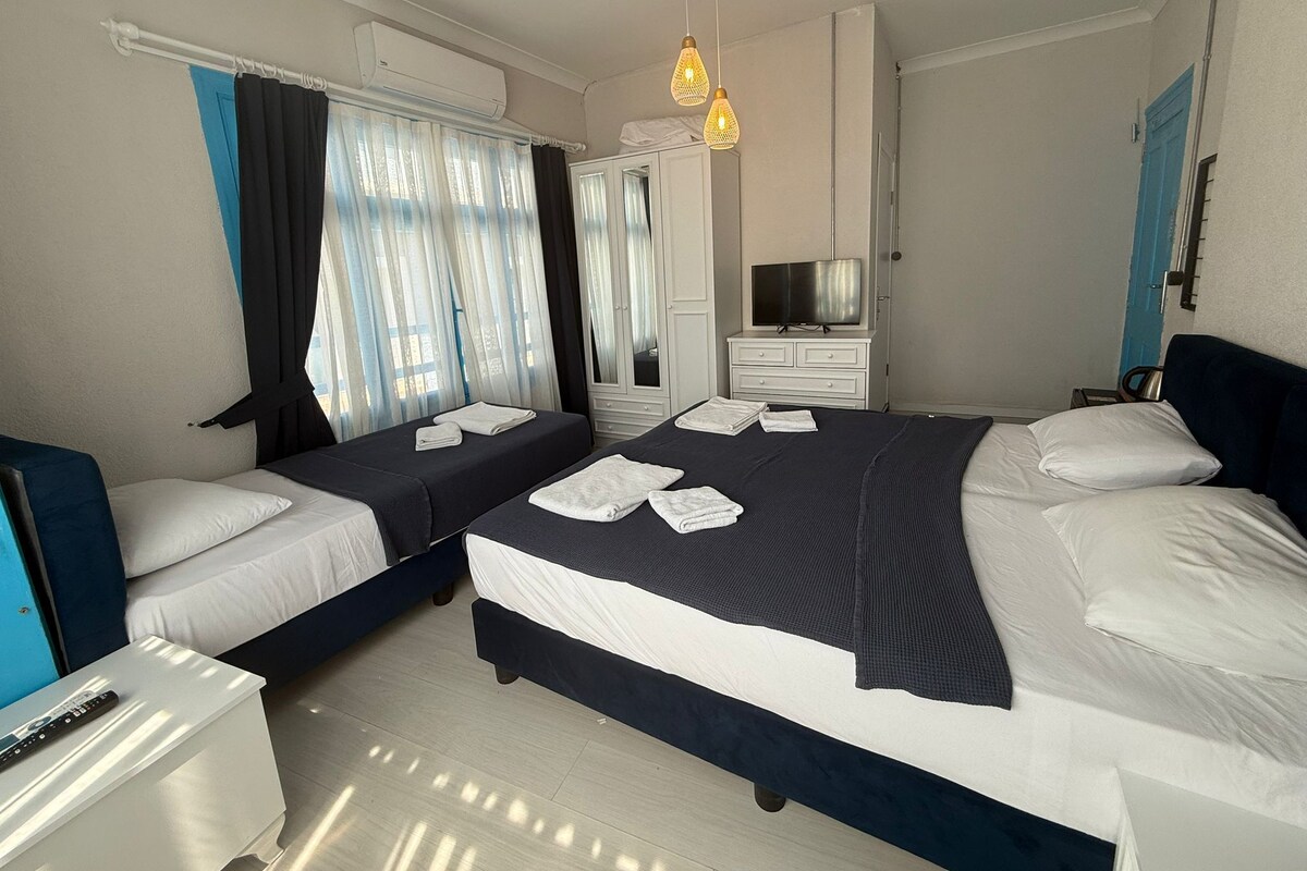A hotel room with two beds, a TV, a wardrobe, and a desk.