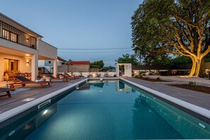 Ein Pool mit Liegestühlen, ein Baum und ein Gebäude mit Balkon.
