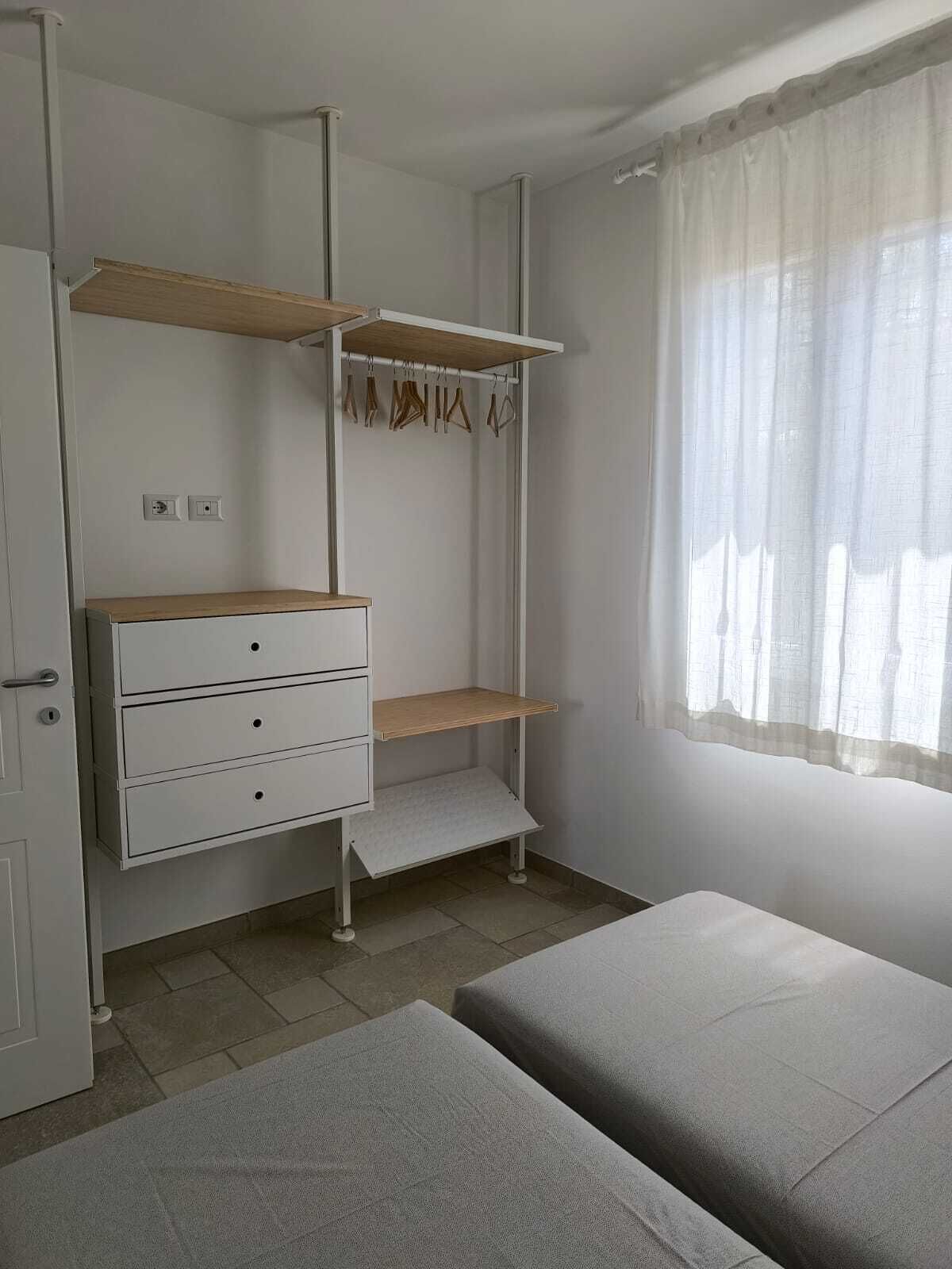 A bedroom with a bed, a wardrobe, and a window with curtains.