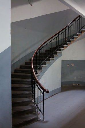 Eine Wendeltreppe mit hölzernem Geländer und Metallspindeln, die zu einer oberen Etage führt.
