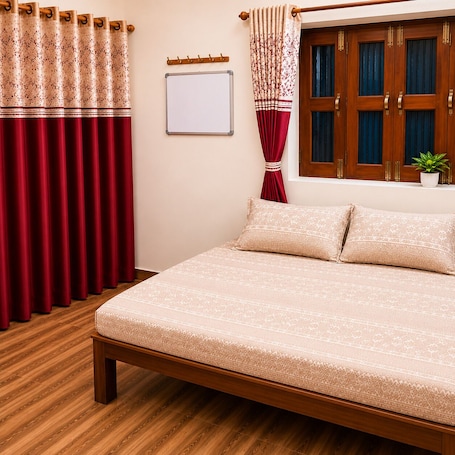 A bedroom with a wooden bed, red curtains, a whiteboard, and a window with curtains.. Balaji Hotel