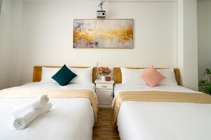 Habitación de hotel con dos camas, una mesita de noche con un reloj y flores, y un cuadro en la pared.