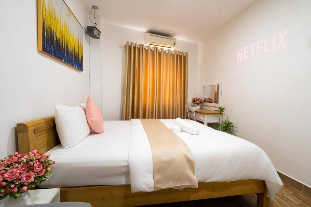 Een hotelkamer met een bed, een bureau, een stoel, een wandairconditioner, een gordijn en een schilderij.
