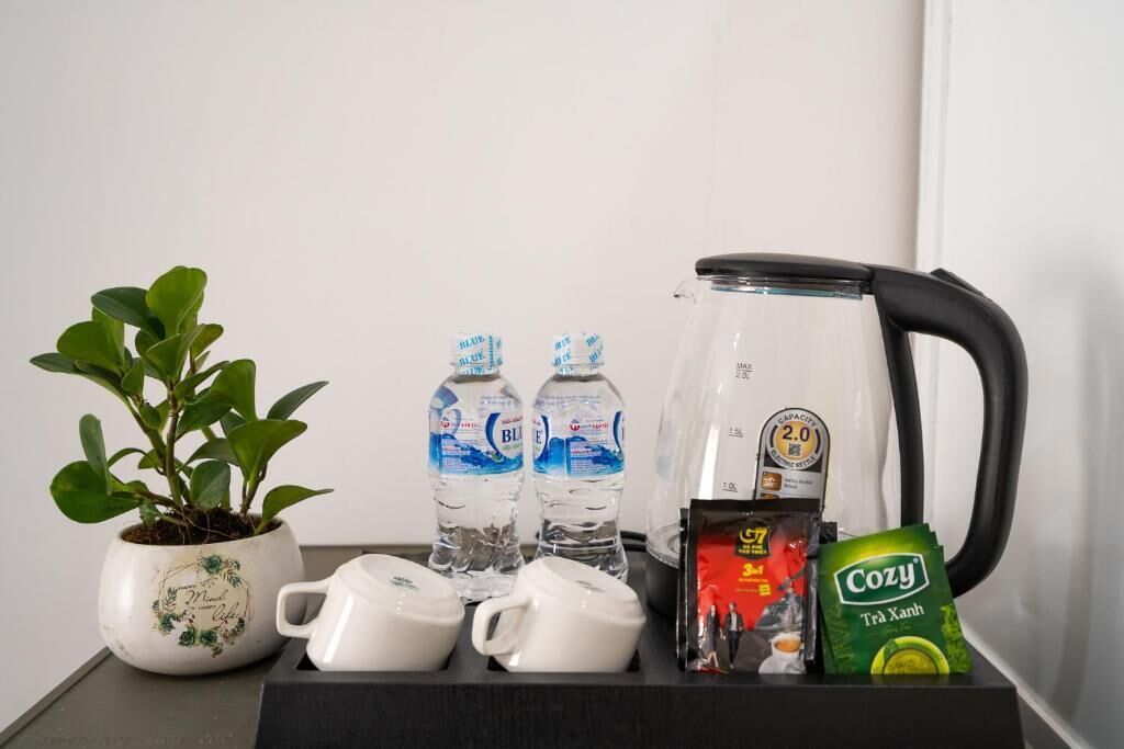 A kitchen area with a coffee maker, water bottles, a potted plant, and a packet of tea.