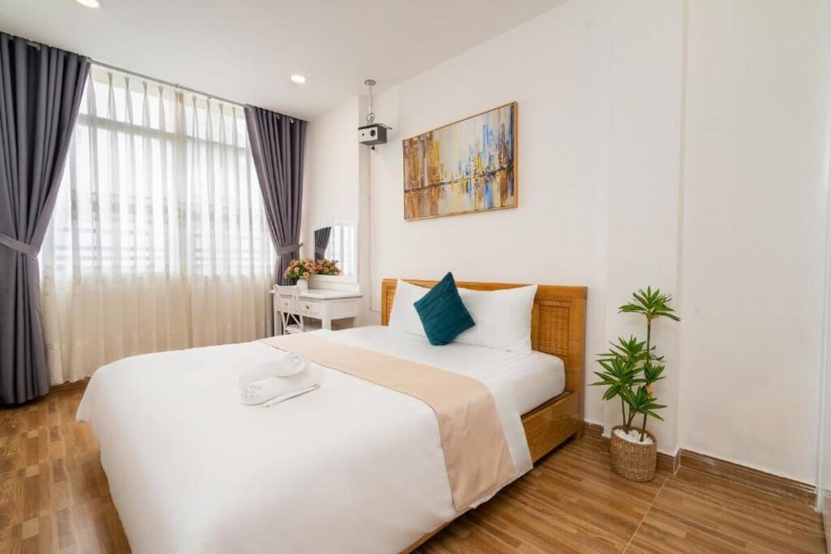 Hotelkamer met een groot bed, een bureau, een stoel, een potplant en een schilderij aan de muur.