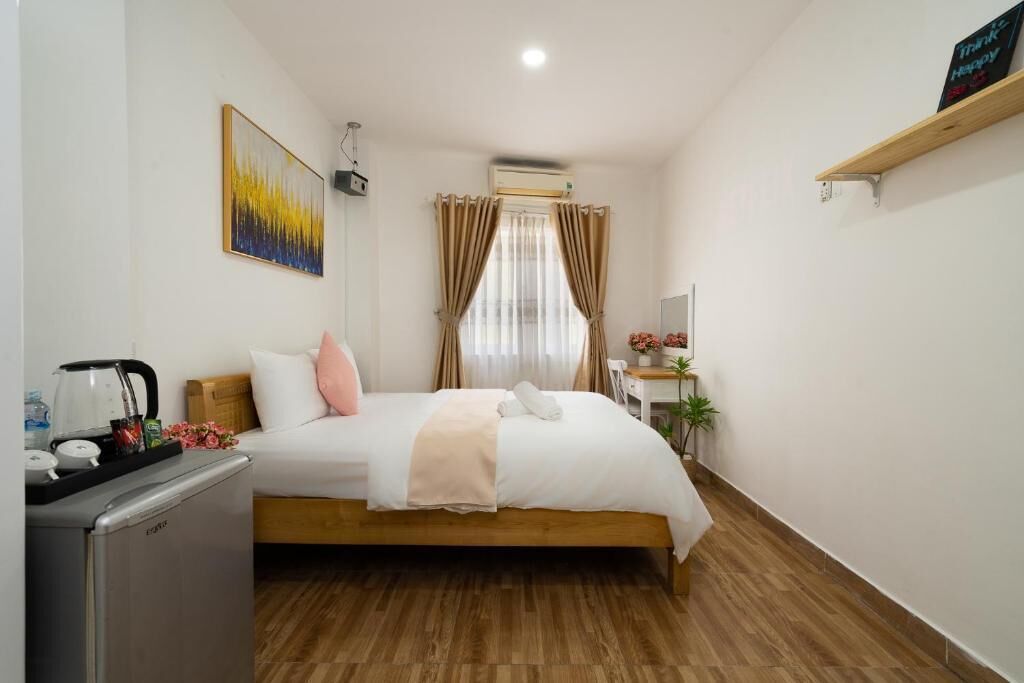 A hotel room with a bed, a desk, a coffee maker, and a small refrigerator.