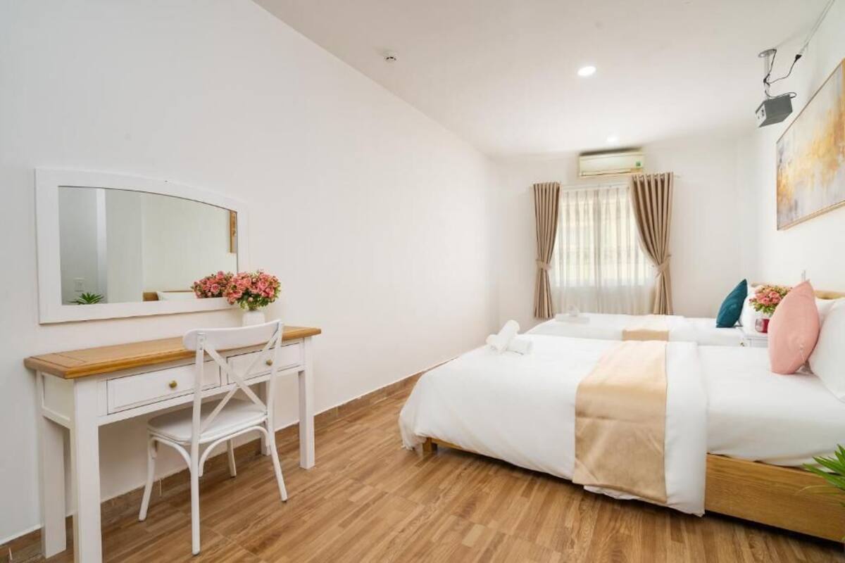 Een slaapkamer met een bed, een bureau, een stoel, een spiegel en een raam met gordijnen.