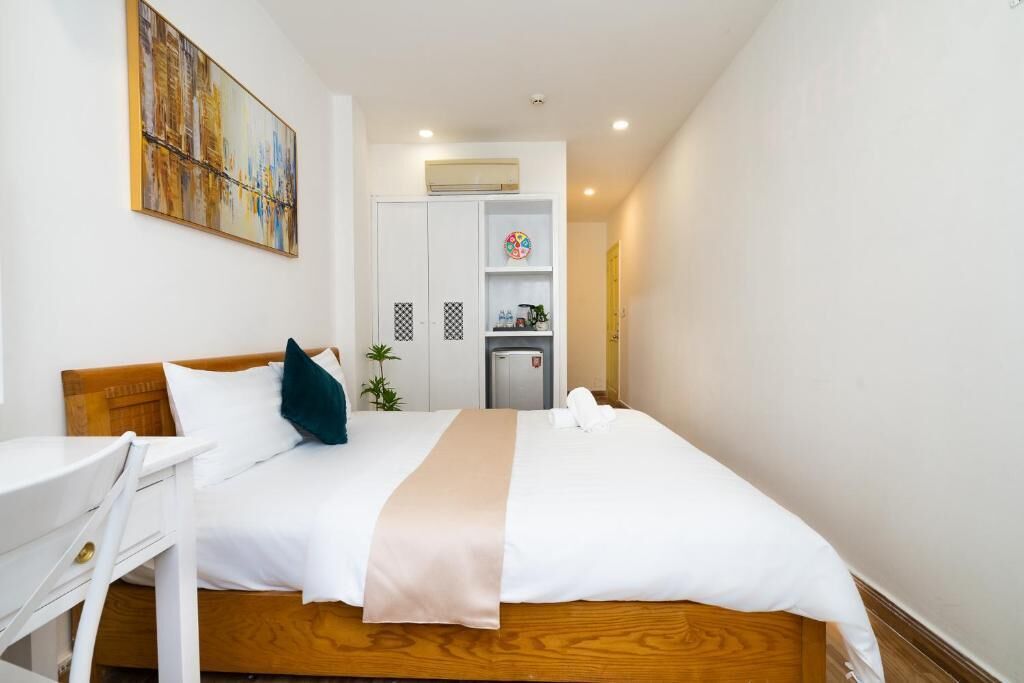 Une chambre d’hôtel comprenant un lit, un bureau, une chaise, un tableau au mur et un coin cuisine.