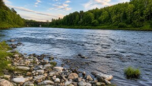 Une rivière aux rives rocheuses, avec un pont en arrière-plan.