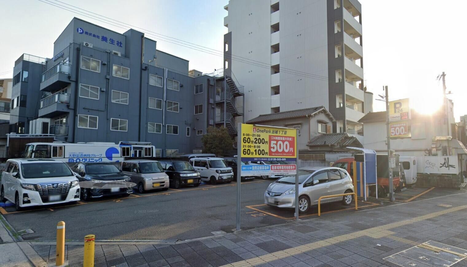 Een parkeerplaats met meerdere auto's, een gebouw met bewegwijzering en een heldere lucht.