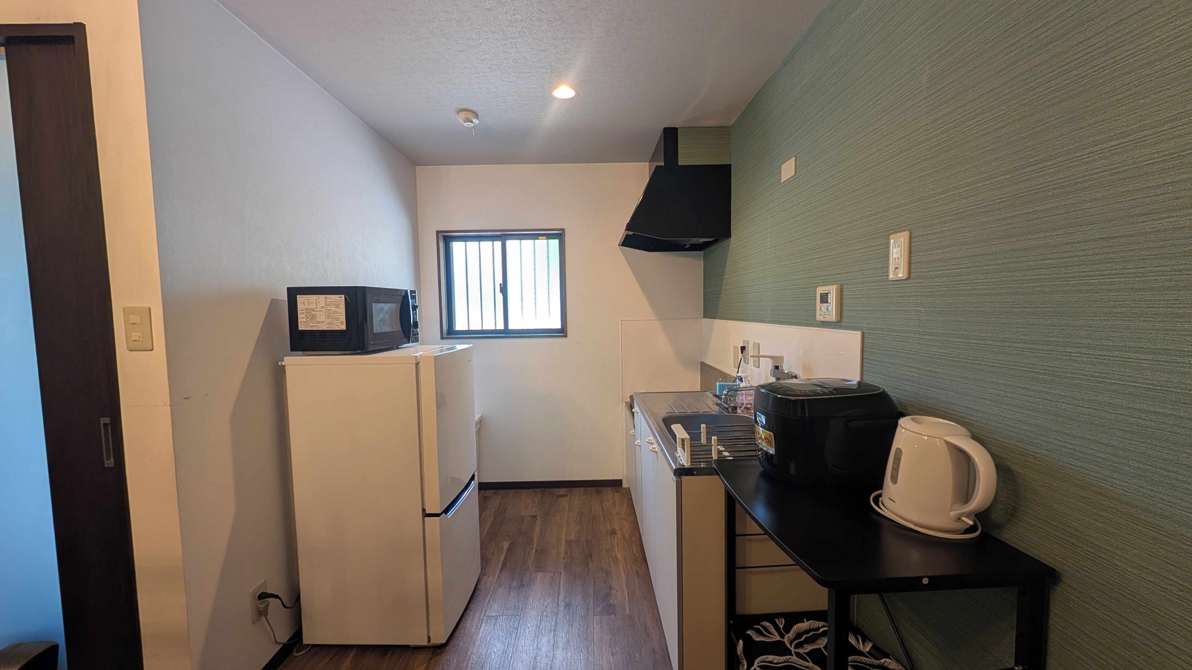 A compact kitchen with a refrigerator, microwave, coffee maker, and a window.